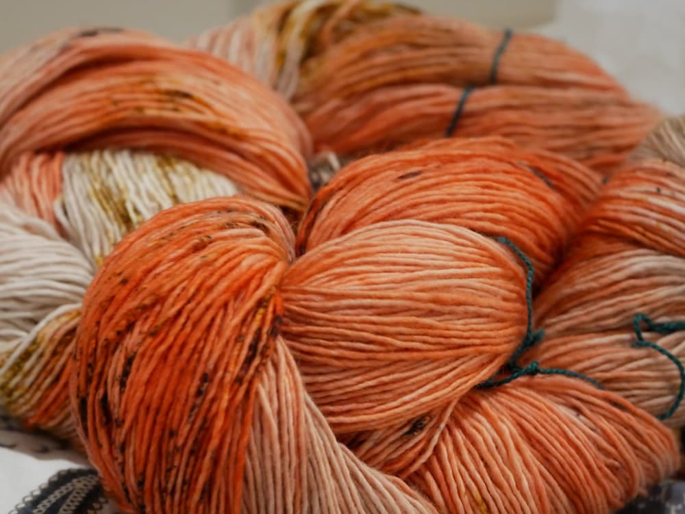 Peach and cream yarn skeins on a white surface